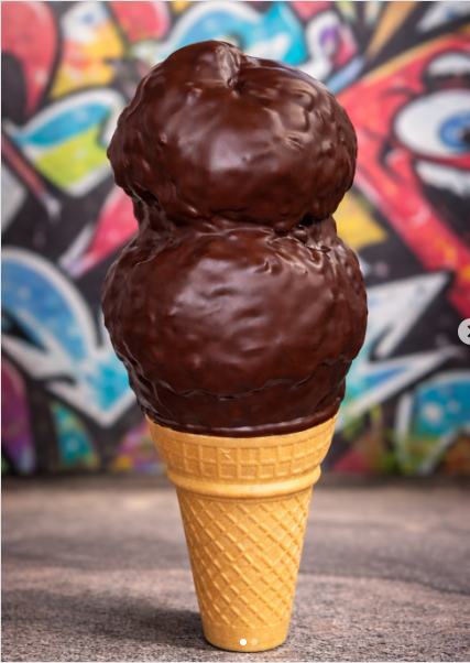 Chocolate hard-dip double scoop cone with colorful graffiti mural backdrop