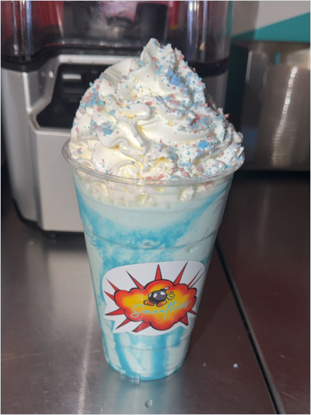 Blue cotton candy milkshake with whipped cream in branded cup